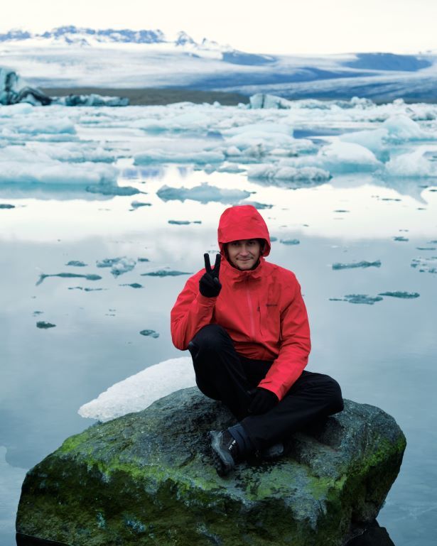 Un hombre sentado en una roca en el lago glaciar Jokulsarlon en Islandia