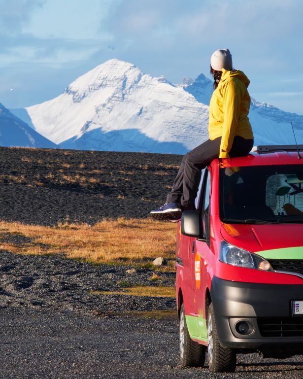 Mujer sobre una camper roja en Islandia