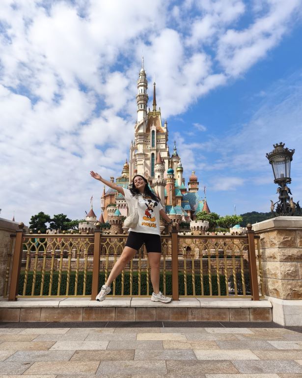 Una chica posa delante del castillo de Disneyland en Hong Kong