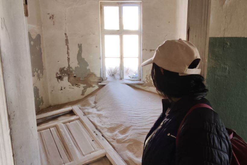 una chica mira una habitación enterrada en el pueblo abandonado de Kolmanskop en Namibia