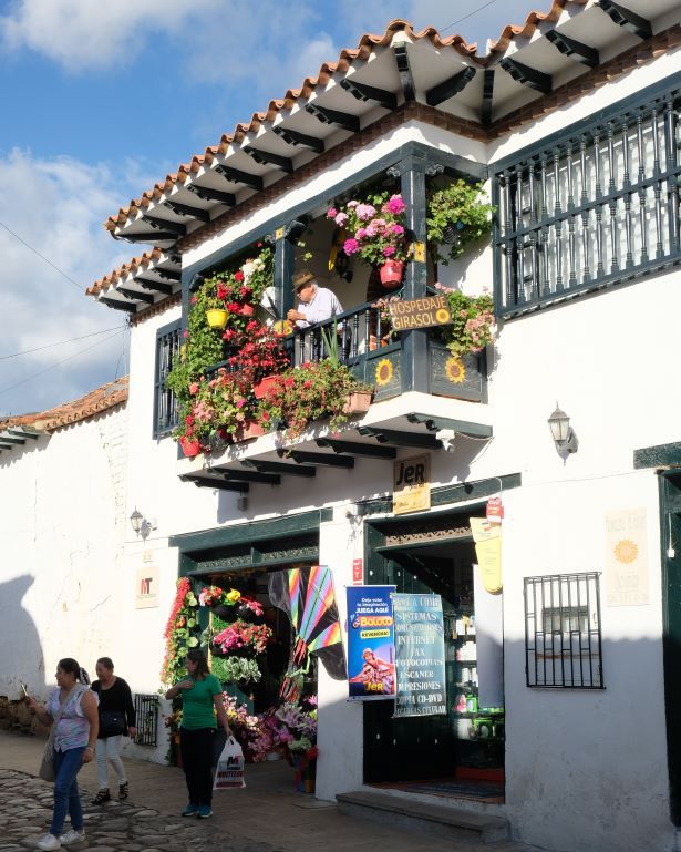 Un hombre se asoma a un balcón ornamentado con flores en la Villa de Leyva en Colombia, cerca de Bogotá
