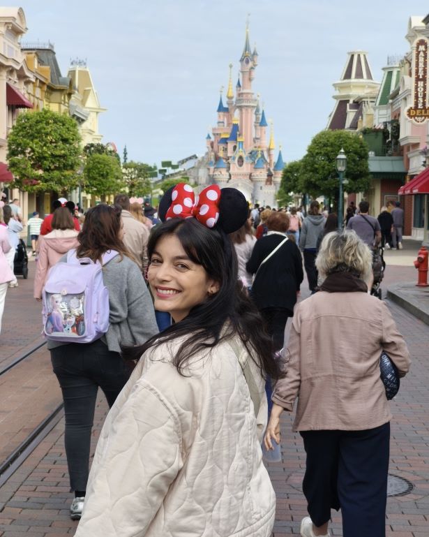 Vistas de la calle principal de Disneyland París con el castillo al fondo y una mujer con una diadema de Minnie en primer plano