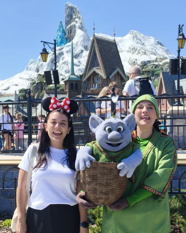 Mujer con diadema de minnie junto a un troll de frozen posando frente al reino de arendelle en disneyland parís, Francia