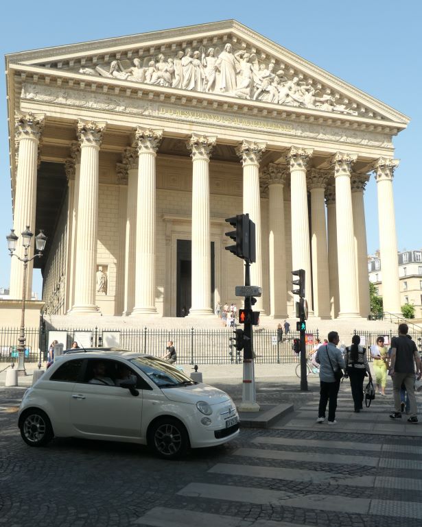 Iglesia de la Madeleine en París con un Fiat 500 parado en un semáforo. Francia.
