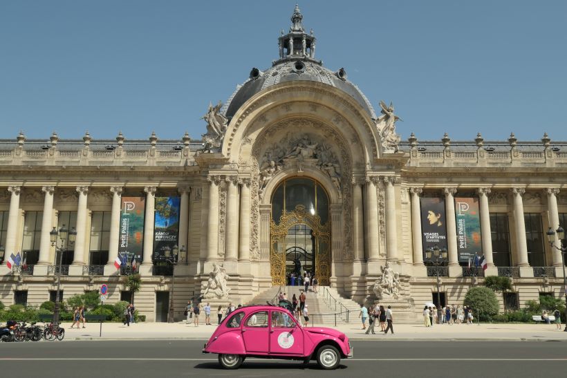 El Petit Palais de París, también museo de bellas artes, con un coche antiguo rosa que cruza enfrente. Francia