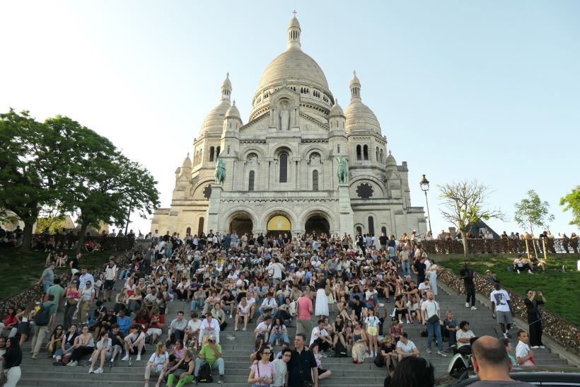 Vistas de la basílica del Sacre Coeur en París, Francia, al atardecer y sus escalinatas repletas de gente