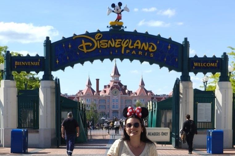 Entrada a Disneyland parís, con mickey en la entrada y una chica posando con orejas de minnie