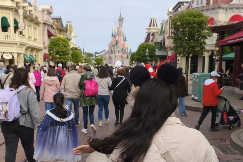 Personas caminando por Main Street en Disneyland París, con el castillo de Blanca nieves de fondo
