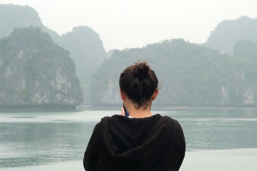 Mujer mirando las rocas de la bahía de halong en Vietnam, rocas kársticas